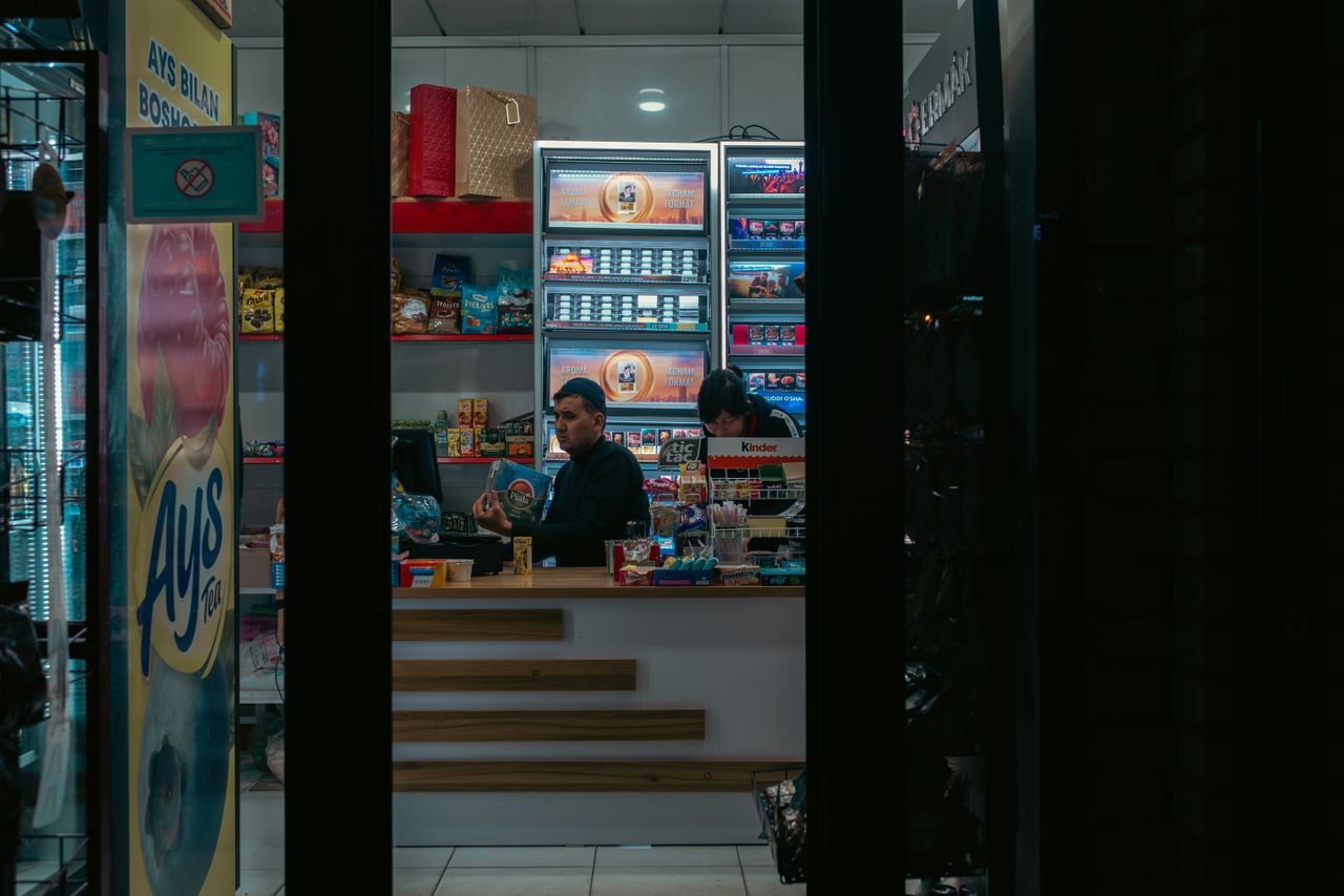 services-03 Interior of a convenience store in Uzbekistan with two adults manning the counter at night.